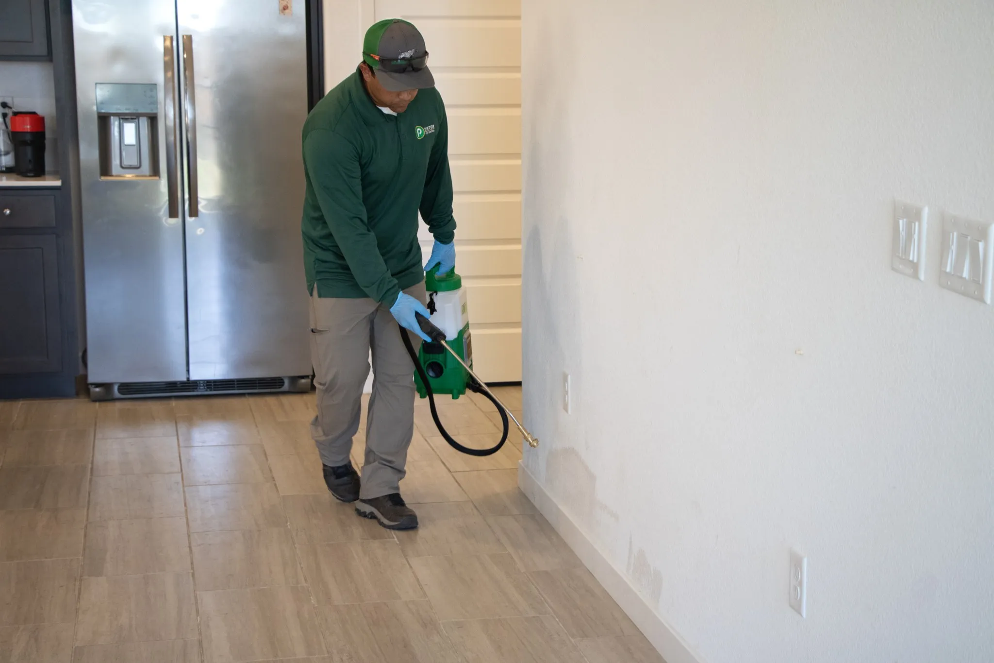 Pointer Pest Control technician treating interior baseboards for fleas inside a Roseville CA home