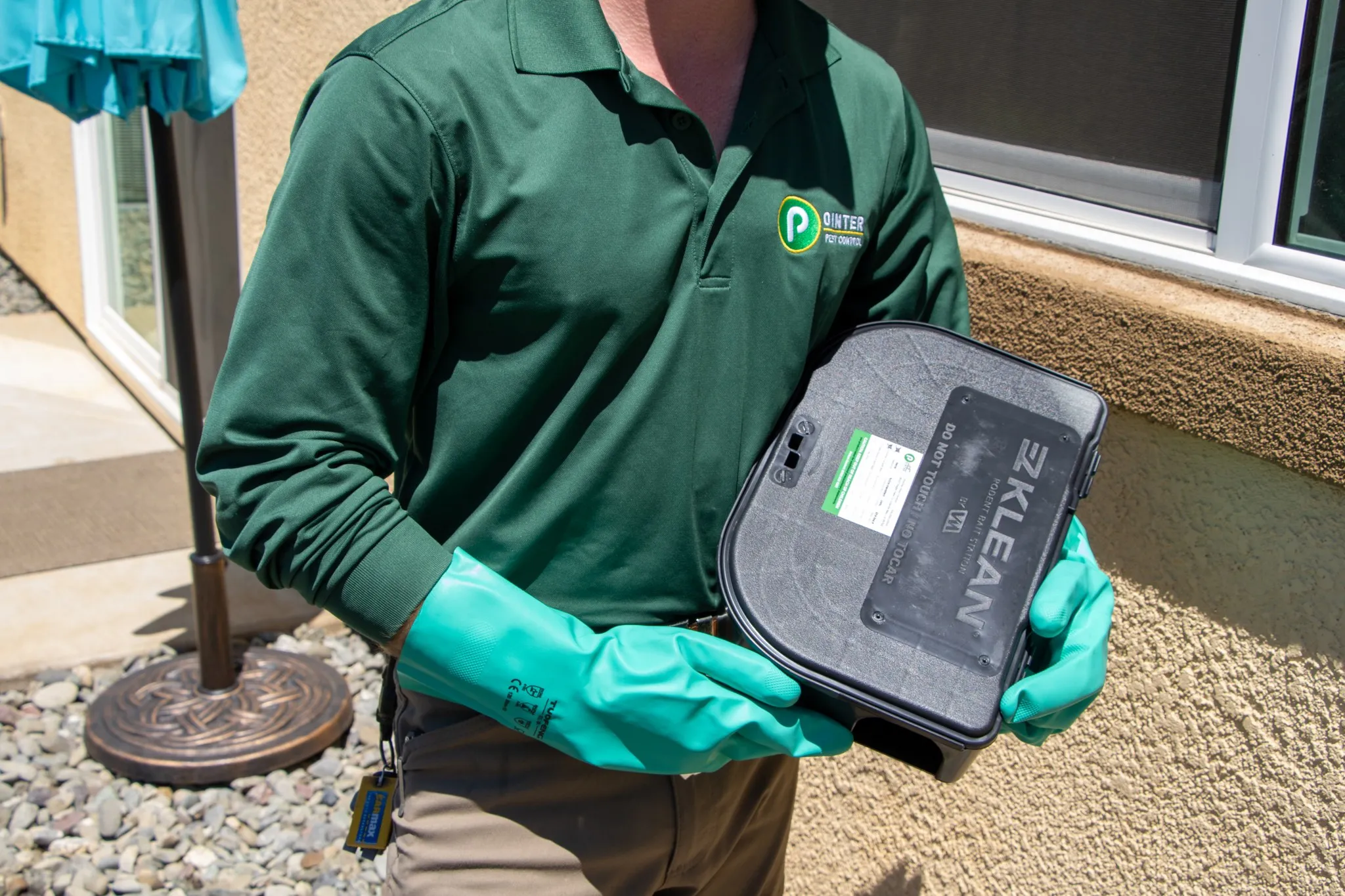 Pointer Pest Control technician holding a tamper-resistant rodent bait station at a Granite Bay CA home