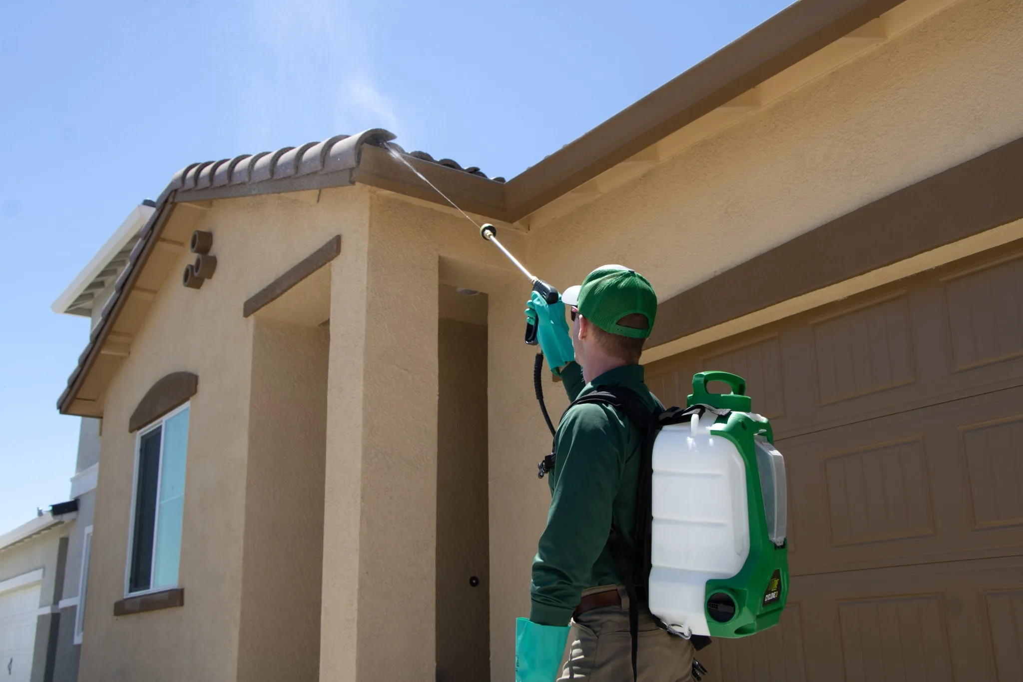 Pointer Pest Control technician spraying under the roofline eaves of a Granite Bay CA home for wasp control